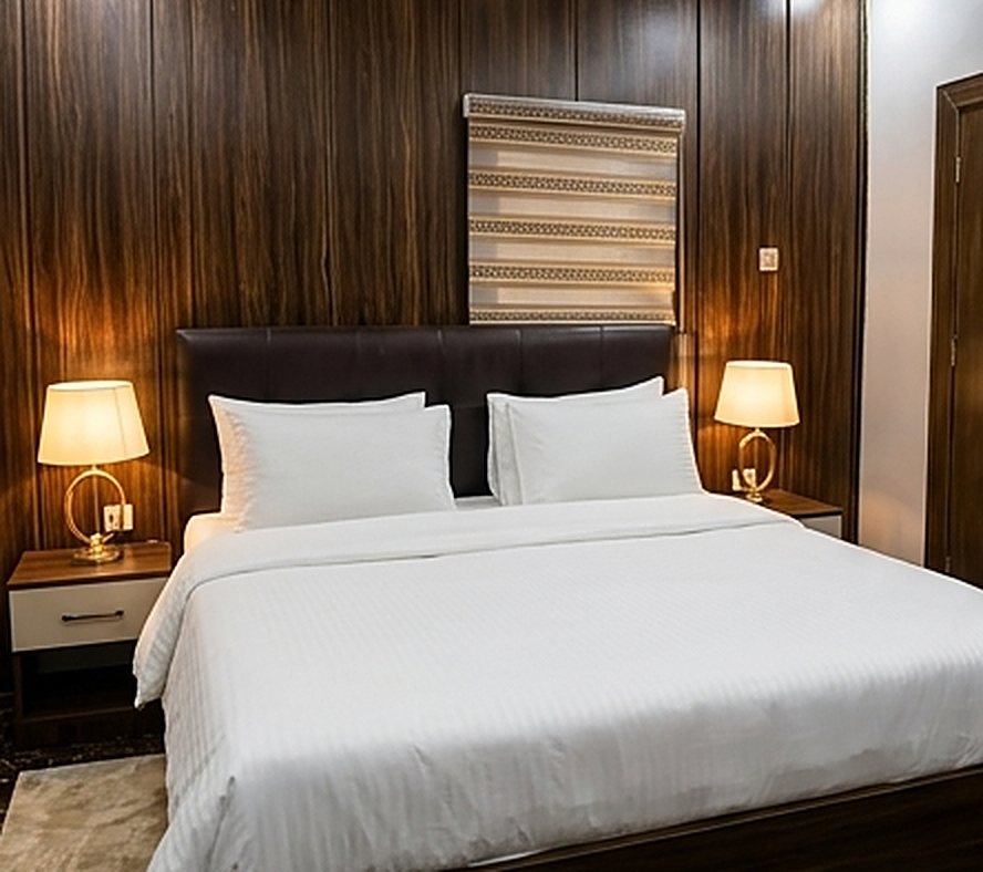 Bedroom with wood-panelled wall and bedside lamps