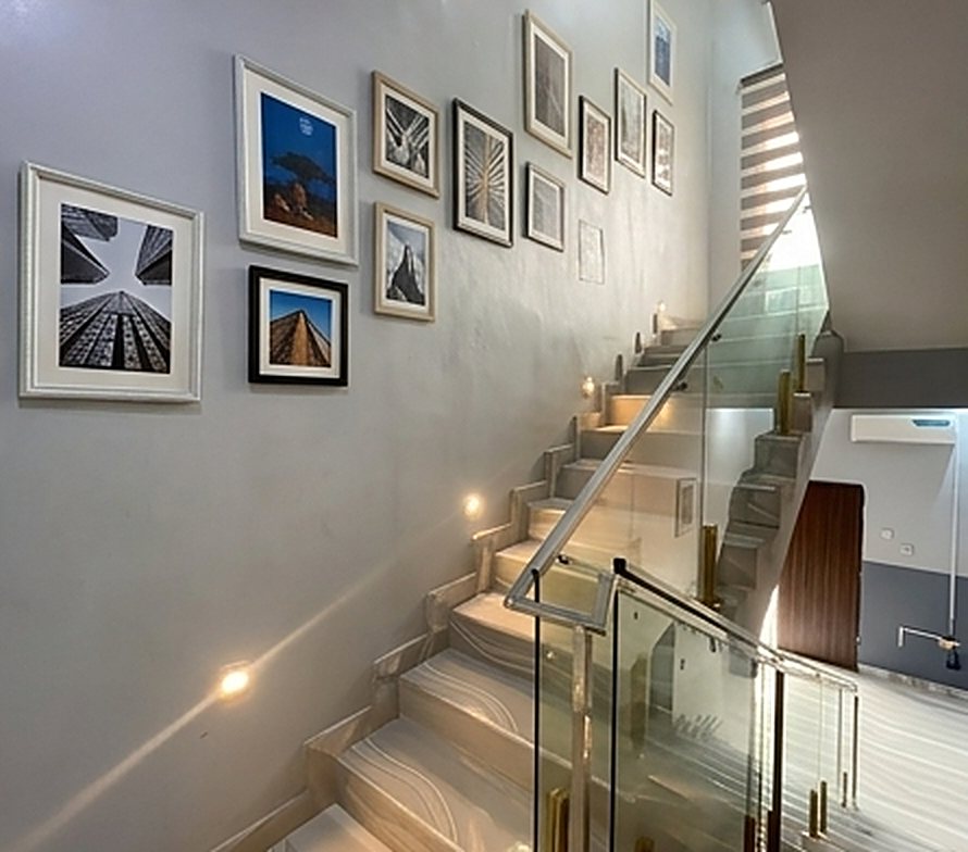 Glass-rail staircase with step lights and gallery wall